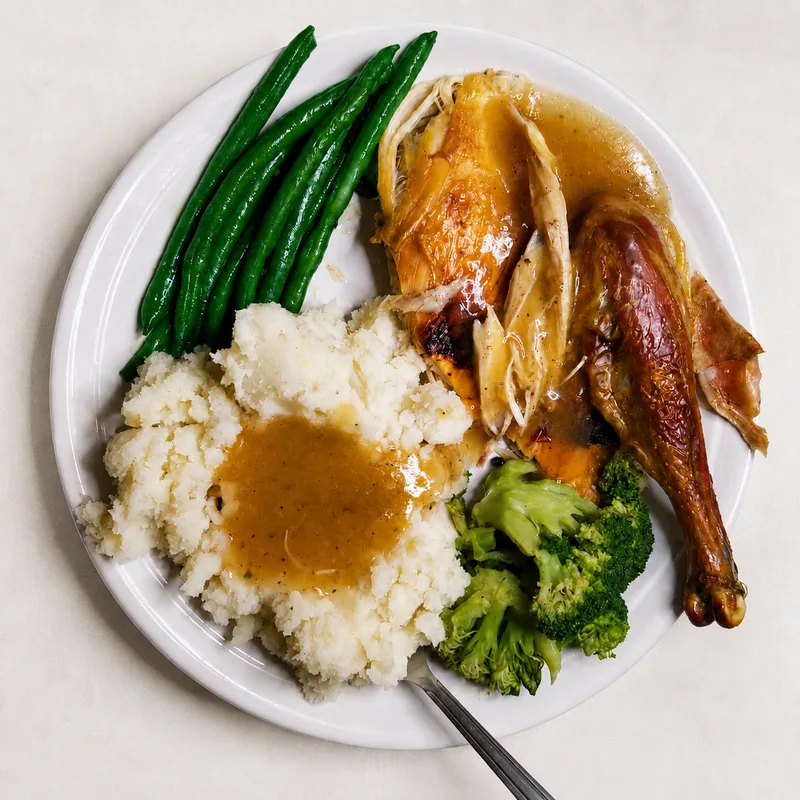 A roasted American Bresse dinner plated with mashed potatoes and gravy, green beans, and broccoli